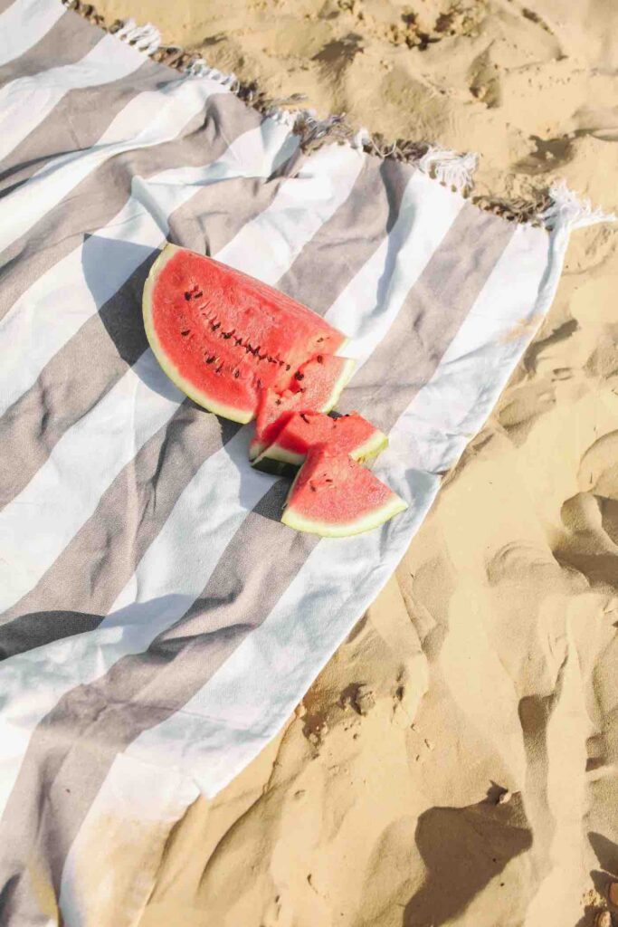Image of a watermelon on top of a blanket at the beach
